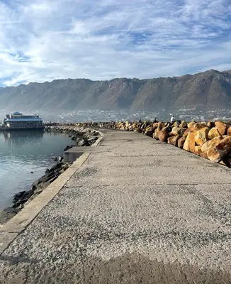 a beach with rocks next to the water at Sealax Cottage Fleurpark in Gordonʼs Bay