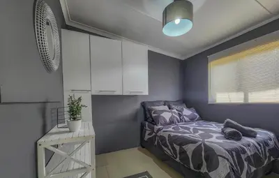 a bedroom with a bed and white cabinets at Sealax Cottage Fleurpark in Gordonʼs Bay