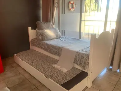 a white bed with pillows on top of it at Sealax Cottage Fleurpark in Gordonʼs Bay