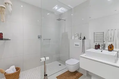 a white bathroom with a toilet and a sink at Sunset Fairway Vista Villa in Cape Town