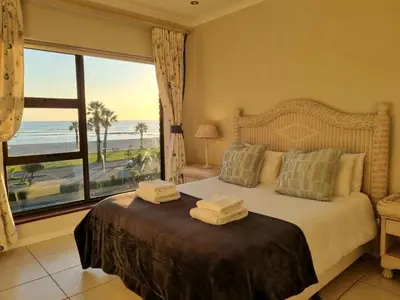 a bedroom with a bed with a view of the ocean at Flat 9, Beachfront 2 Bedroom with Sea View for 4 in Gordonʼs Bay