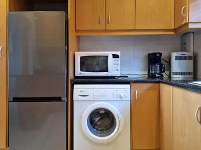 a microwave sitting on top of a washing machine in a kitchen at Flat 9, Beachfront 2 Bedroom with Sea View for 4 in Gordonʼs Bay