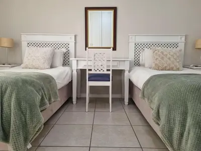 a bedroom with two beds with a desk and a mirror at Flat 9, Beachfront 2 Bedroom with Sea View for 4 in Gordonʼs Bay