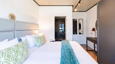 a bedroom with a large white bed with green and white pillows at The Bridgewater Collection 409-Luxury 2 bed Modern Apartment at Century City in Cape Town