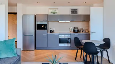 a kitchen with blue cabinets and a table and chairs at The Bridgewater Collection 409-Luxury 2 bed Modern Apartment at Century City in Cape Town
