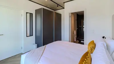 a bedroom with a bed with white sheets and yellow pillows at The Bridgewater Collection 409-Luxury 2 bed Modern Apartment at Century City in Cape Town