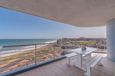 a balcony with a table and a view of the beach at Horizon Bay 903 Fresh Beachfront Hideaway in Cape Town