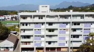 a white apartment building with blue signs on it at The Pearl in the Winelands in Paarl