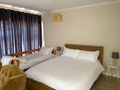 a bedroom with two beds and a chair and a window at Worcester accommodation Putt and Stay in Worcester