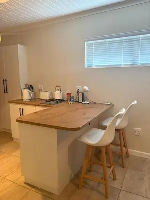 a kitchen with a counter and two white chairs at Worcester accommodation Putt and Stay in Worcester