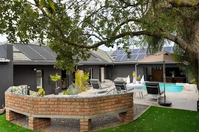 a house with a brick patio with chairs and a pool at Luxury Family Villa with Pool, Gym & Bonfire Area in Cape Town