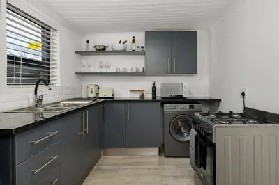 a kitchen with a sink and a washing machine at Luxury Family Villa with Pool, Gym & Bonfire Area in Cape Town