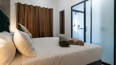 a bedroom with a bed with pillows and a window at AlimamaSpaces The Fynbos Chelsea in Cape Town