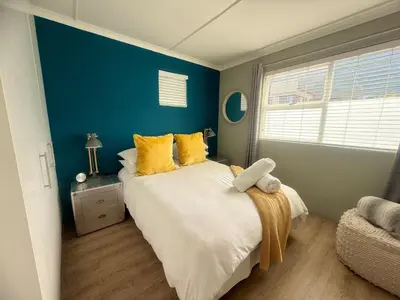 a bedroom with a large bed with yellow pillows at Loft Escape in Onrus with Hot Tub- 2km from beach in Hermanus