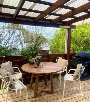 a patio with a wooden table and chairs on a deck at Loft Escape in Onrus with Hot Tub- 2km from beach in Hermanus
