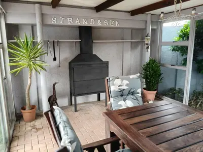 a porch with a stove and a couch and a table at Strand and Sea Cottage in Strand