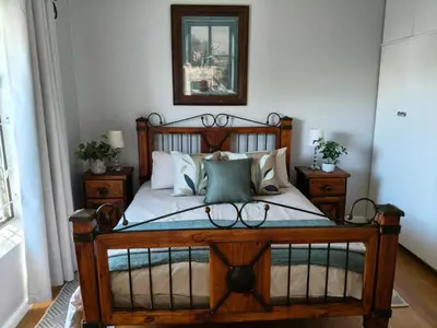 a bedroom with a wooden bed with pillows at Strand and Sea Cottage in Strand