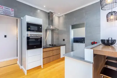 a kitchen with white appliances and wood floors at Burmeister Circle by CTHA in Cape Town