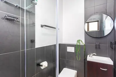 a bathroom with a shower and a toilet and a mirror at Burmeister Circle by CTHA in Cape Town