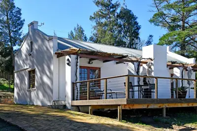 a small white house with a large deck at Topiary Wine Estate & Cottages in Franschhoek