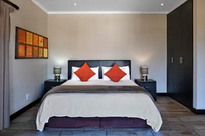 a bedroom with a large bed with orange pillows at Topiary Wine Estate & Cottages in Franschhoek