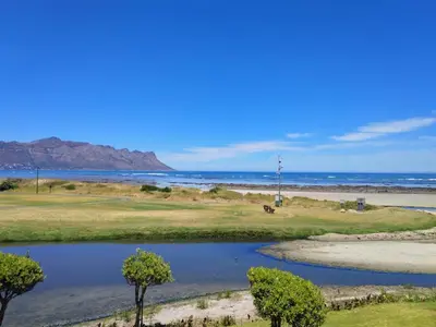 a golf course with the ocean in the background at Seafront Apartment in Secure Golf Estate Strand in Strand