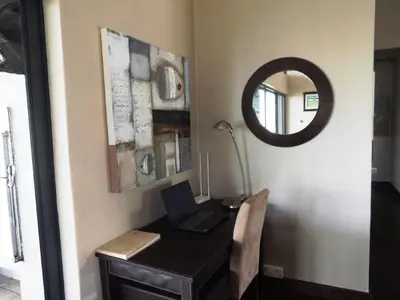 a room with a desk with a laptop and a mirror at Whalesong Villa in Hermanus