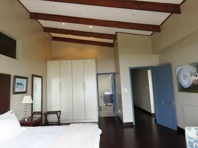 a bedroom with a white bed and a blue cabinet at Whalesong Villa in Hermanus
