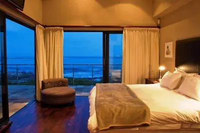 a bedroom with a bed and a view of the ocean at Whalesong Villa in Hermanus