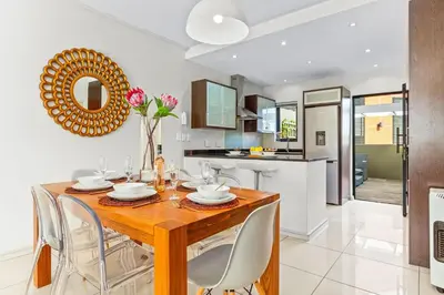 a kitchen and dining room with a wooden table and chairs at Manhattan Wharfside 301 in Cape Town