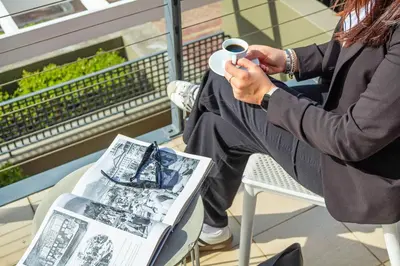 a man sitting on a chair holding a cup of coffee at Manhattan Wharfside 301 in Cape Town
