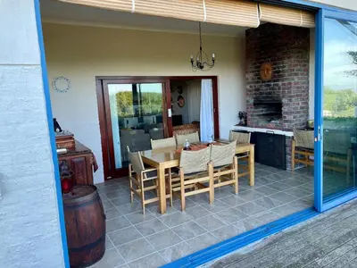 a patio with a table and chairs and a kitchen at Pitkindie Oceanfront Escape in Hermanus