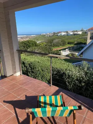 a balcony with a chair and a view of the ocean at Pitkindie Oceanfront Escape in Hermanus