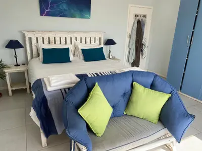 a bedroom with a bed and a blue couch at Sea and Sky Rooiels in Rooiels