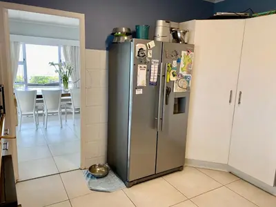 a stainless steel refrigerator in a kitchen with a table at Sea and Sky Rooiels in Rooiels