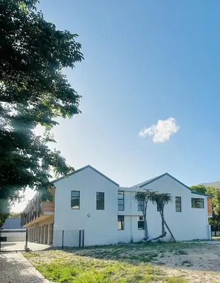 a white building with a tree in front of it at Valley's Embrace Apartment 7 in Hermanus