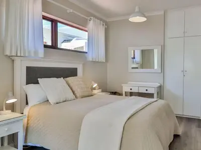 a bedroom with a large bed and a window at Whales & Wonders Guesthouse in Hermanus