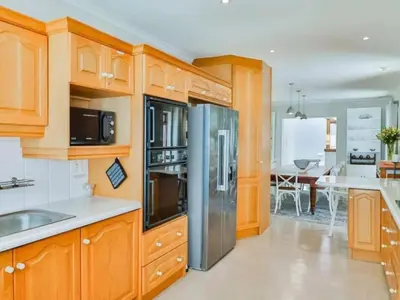 a kitchen with wooden cabinets and stainless steel appliances at Whales & Wonders Guesthouse in Hermanus