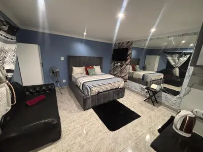 a bedroom with a bed and a couch and a mirror at Browns villa and construction pty ltd in Cape Town
