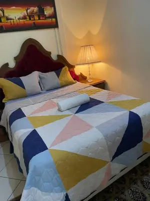 a bed with a colorful quilt on top of it at Harmony Lodge in Elsiesrivier
