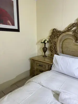 a bedroom with a white bed with a wooden headboard at Harmony Lodge in Elsiesrivier