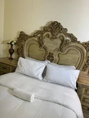 a bed with a large headboard and white sheets and pillows at Harmony Lodge in Elsiesrivier