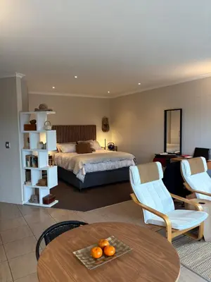 a bedroom with a bed and a table and chairs at Treetops Studio in Cape Town