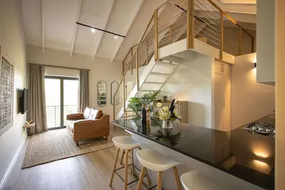 a kitchen and living room with a counter and chairs at Aurora Valley Escape Apartment 9 in Hermanus