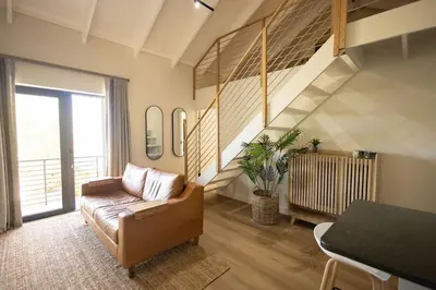 a living room with a couch and a staircase at Aurora Valley Escape Apartment 9 in Hermanus