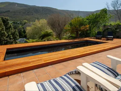 a swimming pool on a deck with two chairs at Leopard Lodge in Hermanus