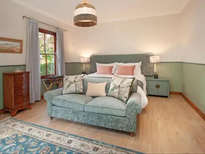 a bedroom with a couch and a bed with pillows at Leopard Lodge in Hermanus