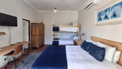 a bedroom with a bed and a desk and a bed and a computer at La Mode Garden Cottage in Paarl