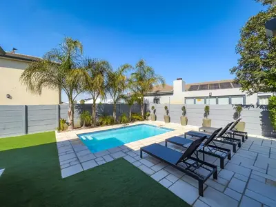 a backyard with a swimming pool and chairs and a house at Peppertree Villa in Brackenfell