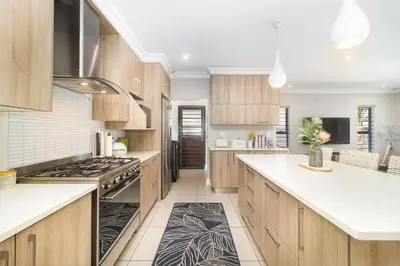 a kitchen with wooden cabinets and white counter tops at Peppertree Villa in Brackenfell